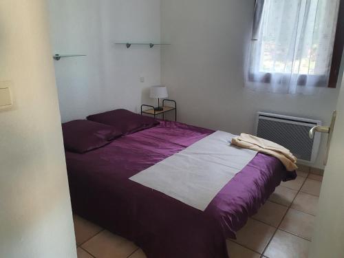 a bedroom with a bed with purple sheets and a window at Aigue Marine. in Canet-en-Roussillon