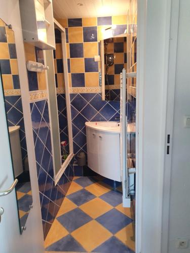a bathroom with blue and yellow tiled walls and a tub at Aigue Marine. in Canet-en-Roussillon