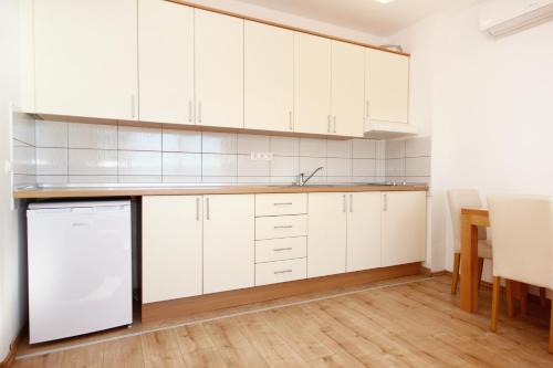 eine Küche mit weißen Schränken und einem Tisch in der Unterkunft Apartment Duce 9437e in Dugi Rat