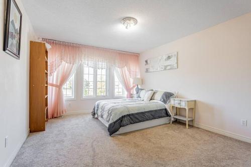 a bedroom with a bed and a window with pink curtains at Luxurious Spacious Dream Home in Richmond Hill