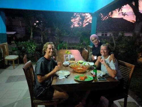 a group of people sitting at a table eating food at Medewisurf-homestay in Airsatang