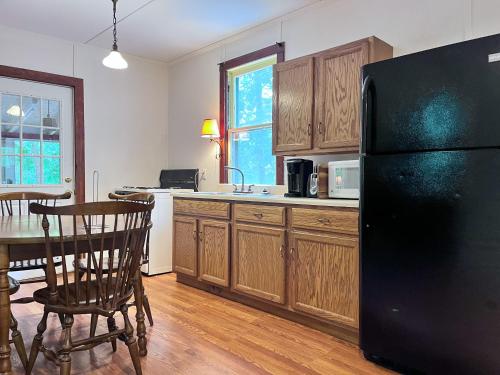 a kitchen with a black refrigerator and a table at Camp Hudson Pines in Corinth