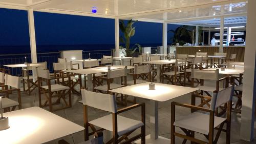 una stanza piena di tavoli e sedie con l'oceano sullo sfondo di Punta Campanella Resort & Spa a Massa Lubrense