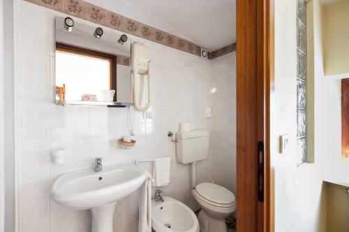 a white bathroom with a sink and a toilet at Dogana Vecchia - Hotel & Residence B&B Ristorante & Pizzeria in Trivignano Udinese