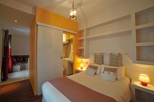 - une chambre avec un grand lit blanc et des oreillers dans l'établissement Studios Archange St Michel, à Lourdes