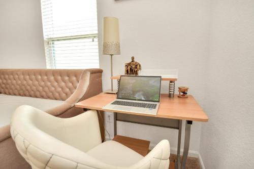 a desk with a laptop on a table with a chair at CHARMING 4 BEDROOMS BROOKSHIRE/KATY WITH GYM in Brookshire