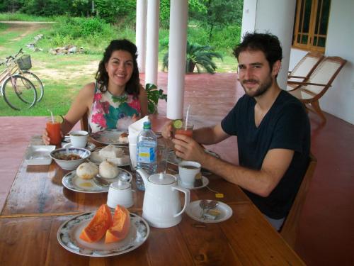 a man and a woman sitting at a table with drinks at Ruins Villa in Polonnaruwa
