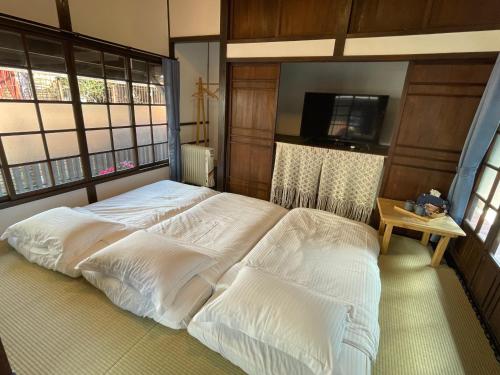 1 dormitorio con 1 cama grande con sábanas blancas en 南庄東村宿舍Nanzhuang Dongchon Homestay, en Nanzhuang