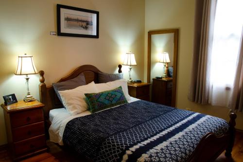 ein Schlafzimmer mit einem Bett, zwei Lampen und einem Spiegel in der Unterkunft Gellibrand River Gallery Accommodation in Gellibrand