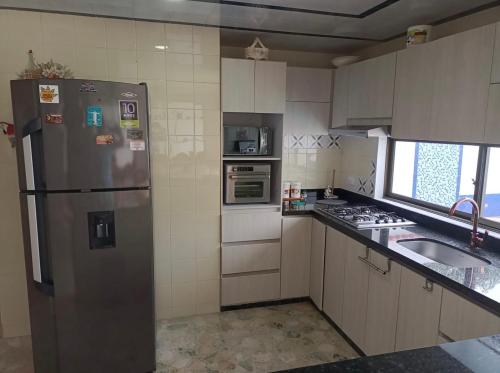 a kitchen with a stainless steel refrigerator and a sink at Hermosa y espaciosa casa familiar en Anapoima in Anapoima