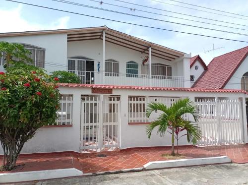 a white house with a white fence and trees at Hermosa y espaciosa casa familiar en Anapoima in Anapoima