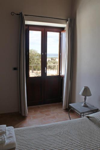 a bedroom with a bed and a door with a window at Pantanelli Di Vendicari in Casa Maccari