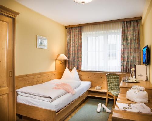 a bedroom with a bed and a desk and a window at Landhotel Steindlwirt in Dorfgastein