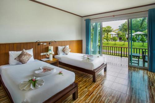 a hotel room with two beds and a balcony at The La Valle'e Resort in Khao Lak