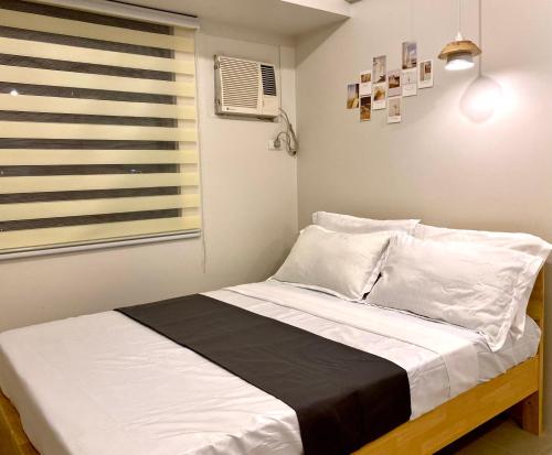 1 dormitorio con 1 cama con sábanas blancas y ventana en Nordic Bleu Staycation at Ayala Serin, en Tagaytay