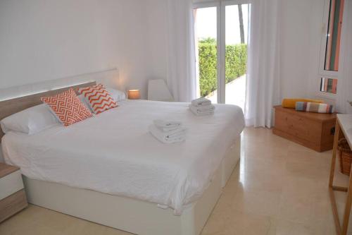 um quarto branco com uma grande cama branca e uma janela em Lovely 2 bedroom unit with private pool em Sotogrande