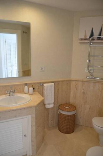 a bathroom with a sink and a toilet and a mirror at Lovely 2 bedroom unit with private pool in Sotogrande