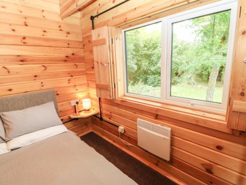 a bedroom in a log cabin with a bed and a window at Pheasant in Barnard Castle