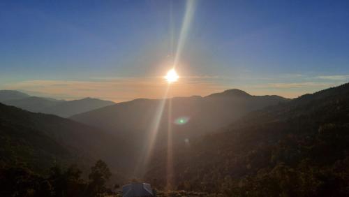een zonsondergang boven een bergketen met de zon die schijnt bij The Swarna Homestay in Darjeeling