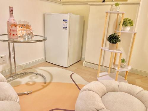 a living room with a refrigerator and two tables at Mermaid's Secret-Bontique Homestay in Qingdao