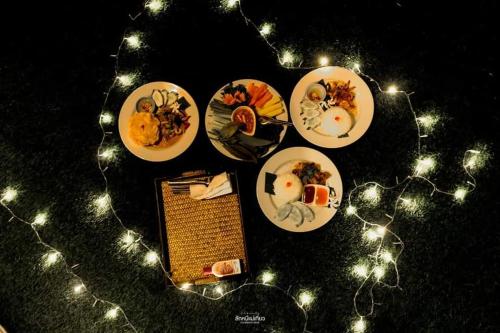 a group of plates of food on a table with lights at Phu Siab Mhok@KhaoSok in Khao Sok