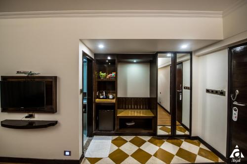 a room with a television and a checkered floor at Hotel Abigail Goradia's in Shirdi