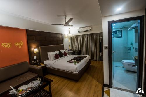a hotel room with a bed and a bathroom at Hotel Abigail Goradia's in Shirdi