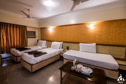 a hotel room with two beds and a table at Hotel Abigail Goradia's in Shirdi