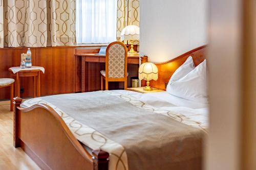 a bedroom with a bed with a desk and a chair at Hotel-Restaurant Minichmayr in Steyr