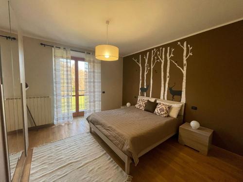 a bedroom with a bed with a tree mural on the wall at Villa Glory Mountain Lake Iseo Hospitality in Bossico
