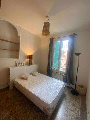 een slaapkamer met een wit bed en een raam bij Nice port : cosy appartement au calme in Nice