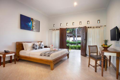 1 dormitorio con cama, mesa y escritorio en Royal Regantris Villa Karang, en Gili Air