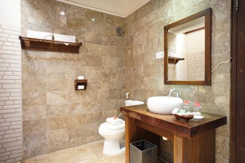 a bathroom with a sink and a toilet and a mirror at Royal Regantris Villa Karang in Gili Air