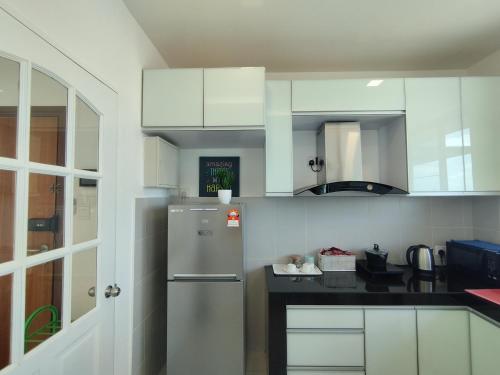 een keuken met witte kasten en een koelkast bij ONE Homestay A 6Pax 2Rooms in Sibu