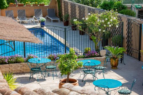 eine Terrasse mit Tischen und Stühlen neben einem Pool in der Unterkunft Casa-Belle Chambres d hotes in Sérignan