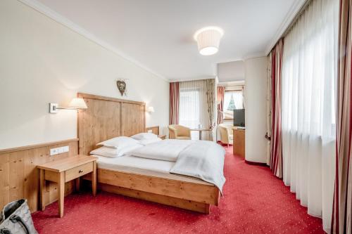 a bedroom with a large bed and a red carpet at Hotel Weisses Lamm in See