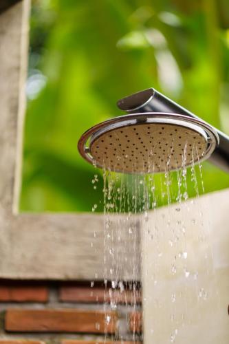 a shower with water coming out of it at Coco Garden Pool Villas in Kubutambahan
