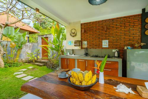 a bowl of bananas on a wooden table in a kitchen at Coco Garden Pool Villas in Kubutambahan