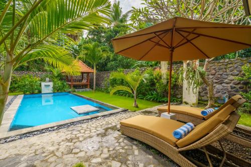 a pool with two lounge chairs and an umbrella at Coco Garden Pool Villas in Kubutambahan