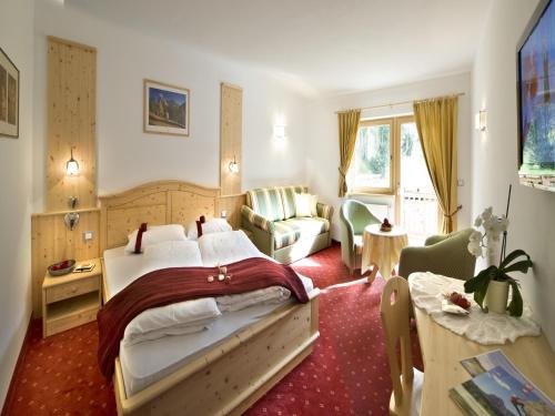 1 dormitorio con cama, sofá y mesa en Hotel Florian, en Selva di Val Gardena