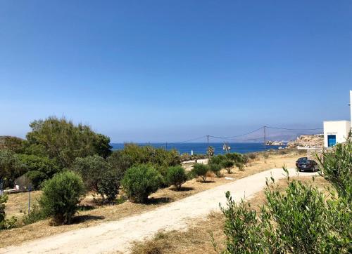 a dirt road with trees and a bridge in the background at A Cycladic-architecture Beach House in Koumbara in Tzamaria