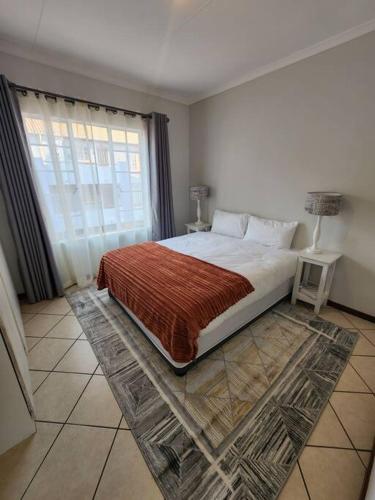 a bedroom with a large bed and a window at Elegant 2 bed apartment next to Gautrain Centurion in Centurion