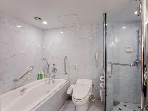 a bathroom with a tub and a toilet and a shower at Nishitetsu Grand Hotel in Fukuoka