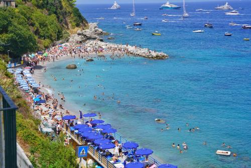 eine Gruppe von Menschen am Strand mit blauen Sonnenschirmen in der Unterkunft Casa Adelaide in Capri