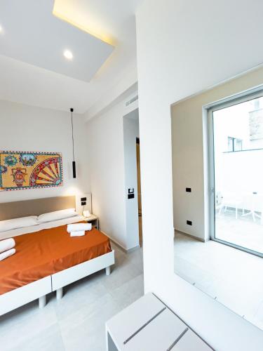 a white bedroom with a bed and a large window at MARINO WELLNESS in Ali Terme