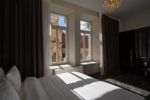 a bedroom with a white bed and two windows at St Palace Hotel in Vilnius