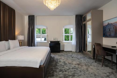 a bedroom with a bed and a desk and windows at St Palace Hotel in Vilnius