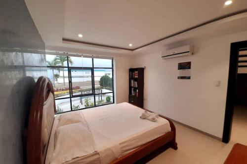 a bedroom with a bed and a large window at Espectacular casa grande vacacional en Manta! in Manta
