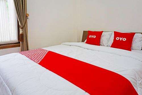 un letto rosso e bianco con due cuscini rossi sopra di OYO LIfe 91571 Hotel Ss Bukit Cemara Syariah a Batu