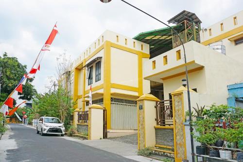 ein gelbes Gebäude mit einem davor geparkt in der Unterkunft OYO 91580 Kost Bougenville Syariah in Madiun